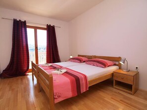 Une chambre à coucher avec un lit en bois, deux tables de chevet, une commode et une fenêtre avec des rideaux.