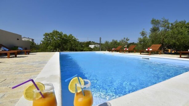 Une piscine avec des chaises longues et une boisson à portée de main.