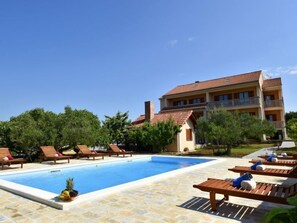 Un espace piscine avec des chaises longues et un bâtiment doté de balcons.