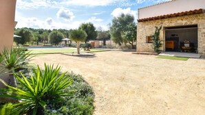 Un patio con un edificio de piedra, una piscina y abundante vegetación.