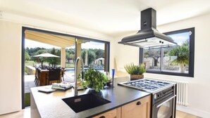 Una cocina moderna con una isla central, horno empotrado y vistas al patio exterior.