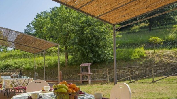 Ein Essbereich im Freien mit Tisch für zwei Personen, beschattet durch eine Holz-Pergola.
