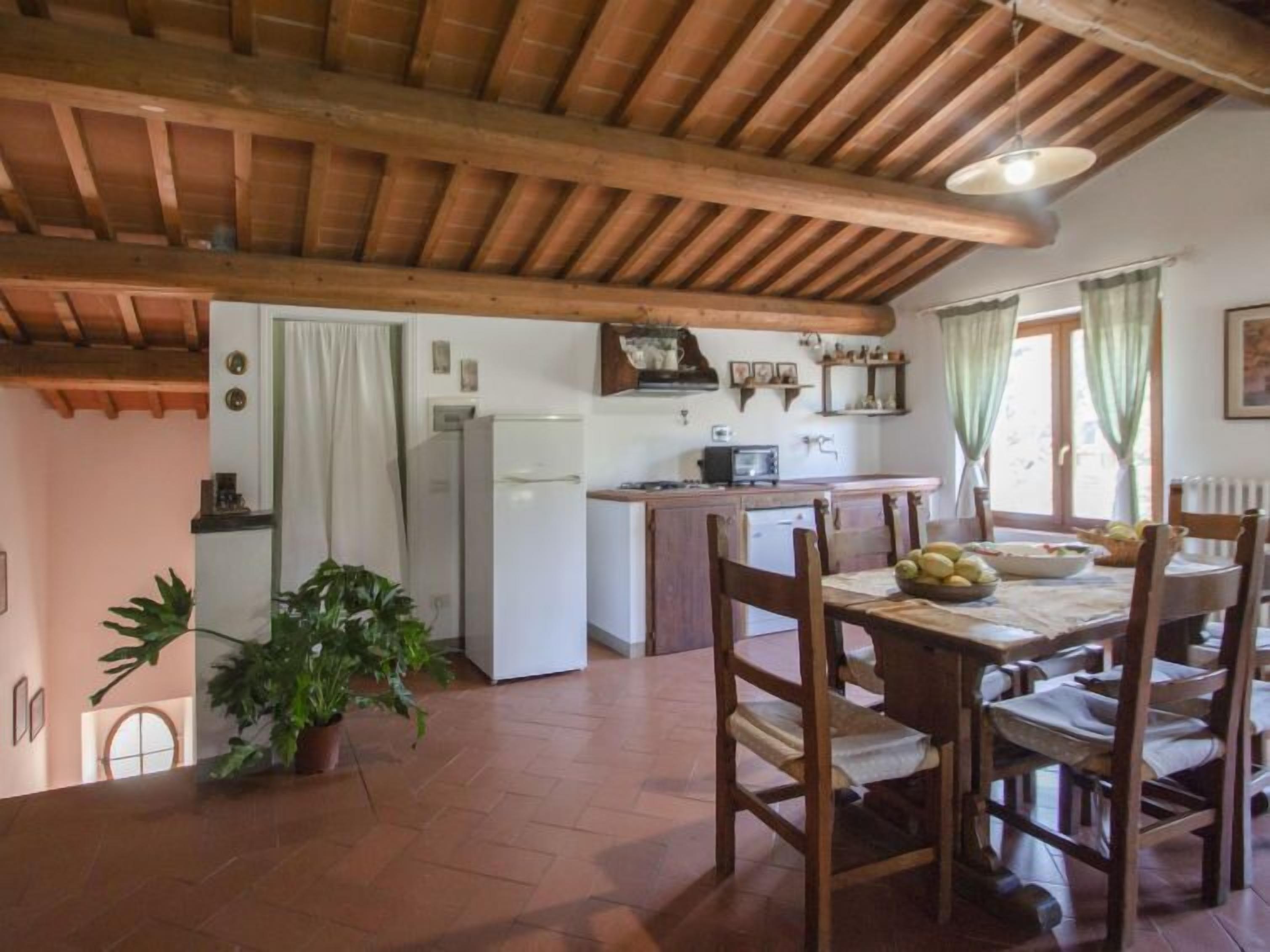Una cucina rustica con travi in legno, un tavolo da pranzo con sedie e un frigorifero.