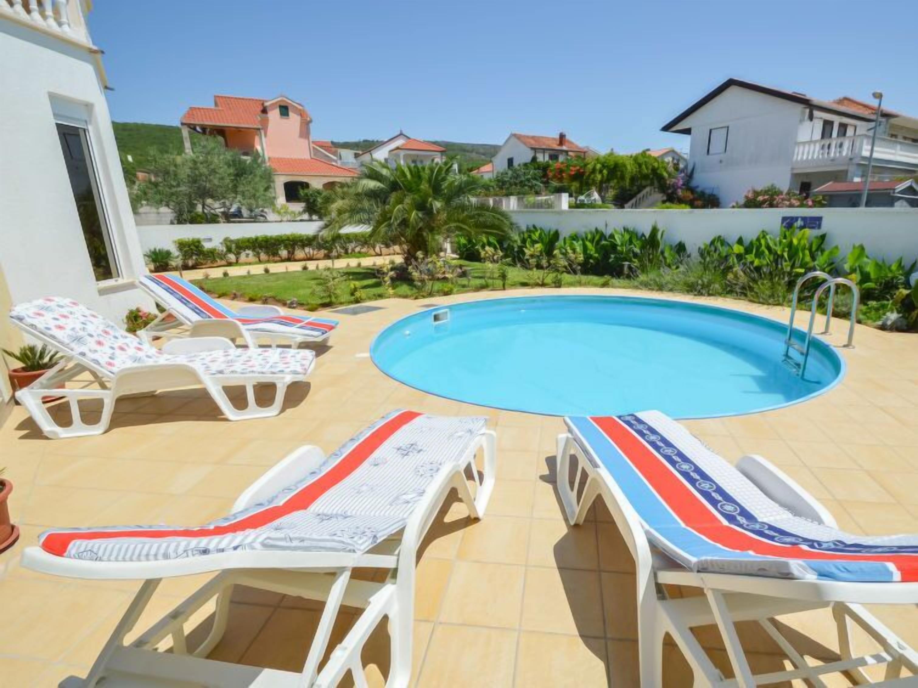 Une piscine avec des chaises longues et une terrasse carrelée.