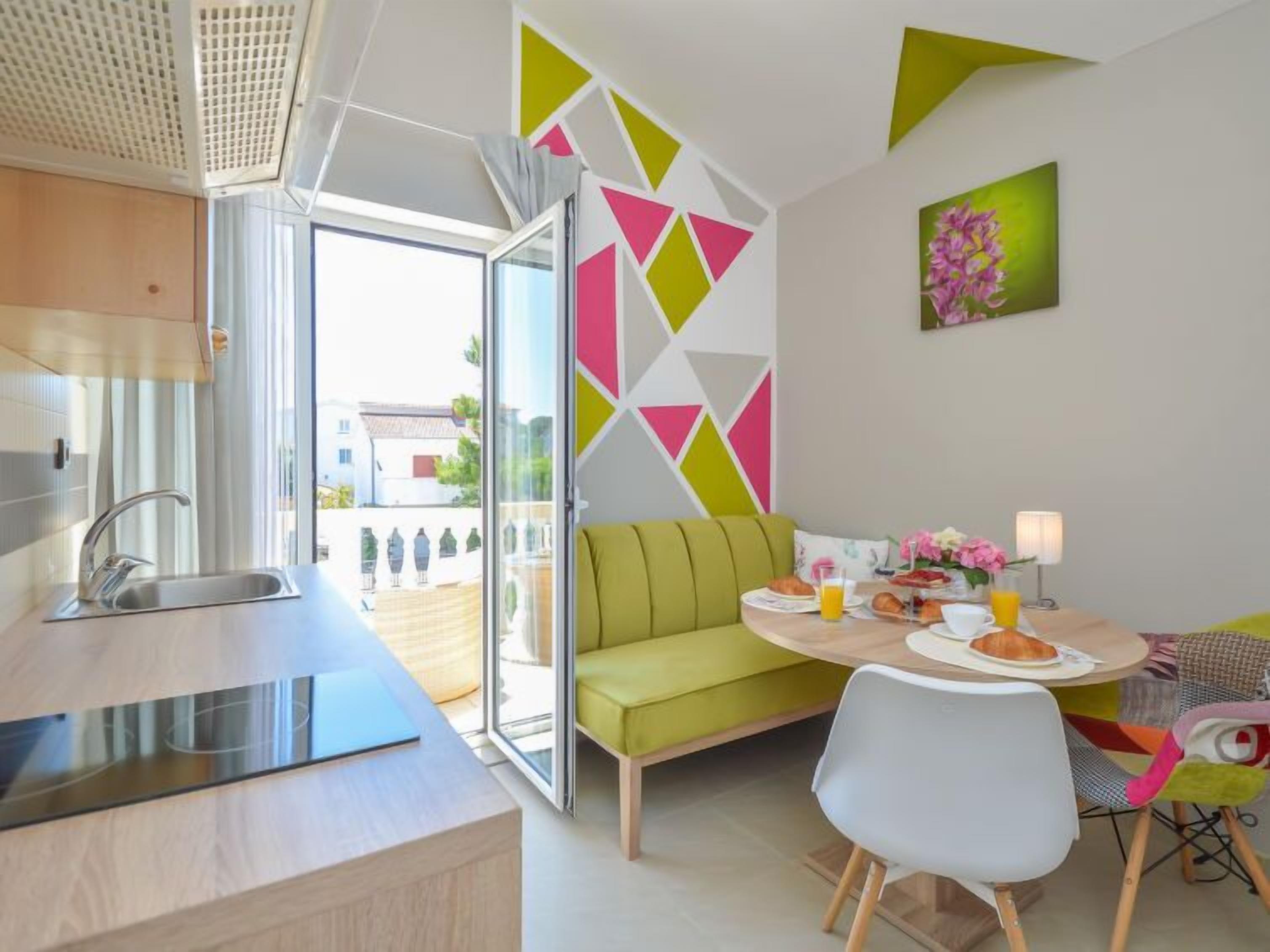 Eine moderne Küche mit Spüle und einem Essbereich, ausgestattet mit einem grünen Sofa und einem Tisch, der für ein Frühstück gedeckt ist.