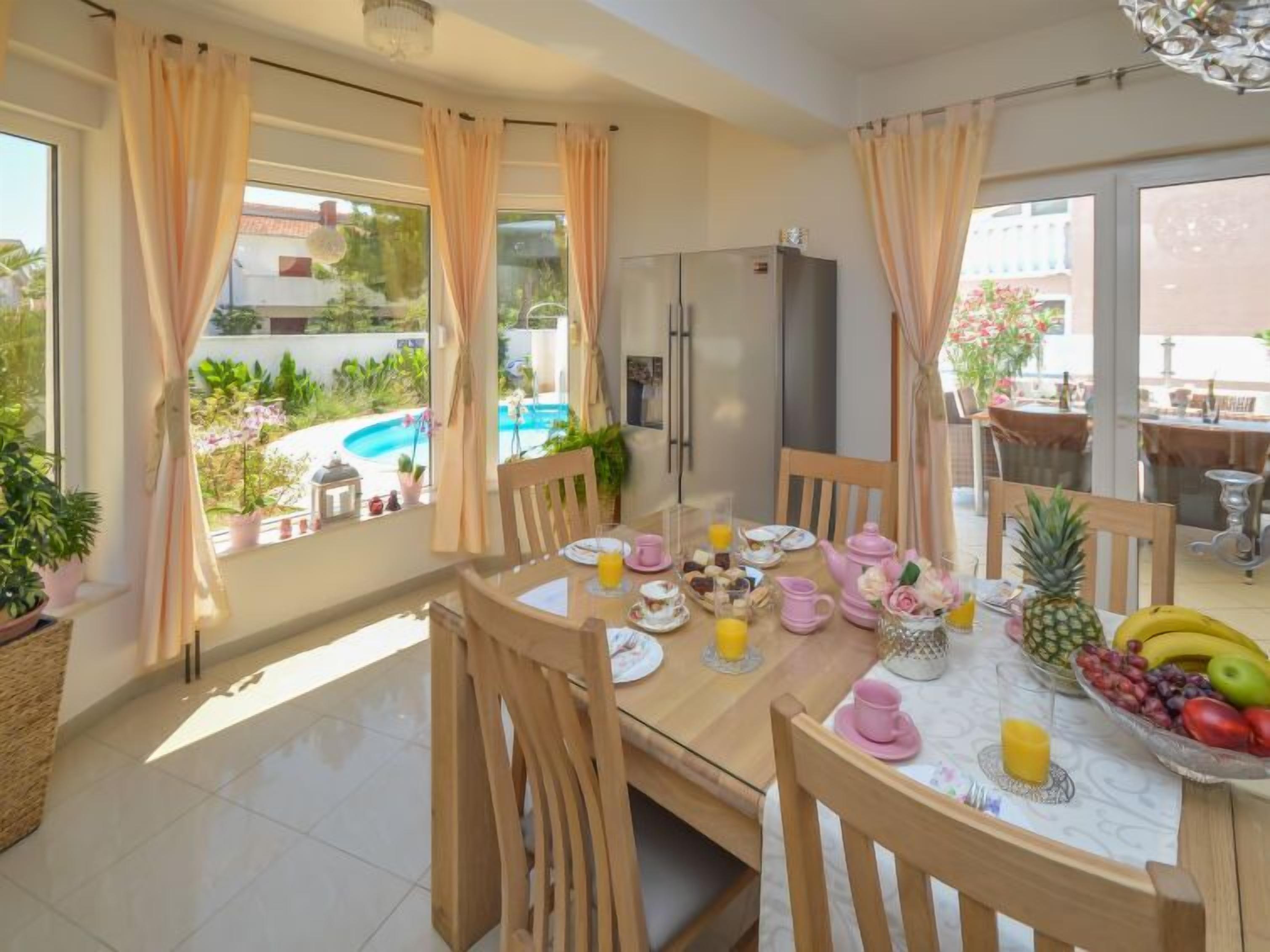 Un coin repas avec une table mise pour le petit-déjeuner, un réfrigérateur et une vue sur une piscine.