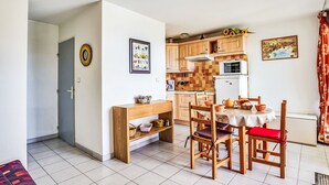 Ein kompakter Wohnraum mit Küchenzeile, einem Essbereich mit Tisch und Stühlen sowie einer Couch.