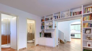 A modern living room with a sofa, a TV, and a bookshelf filled with books. - Vacation home Tommy by Interhome (Poreč/Nova Vas)