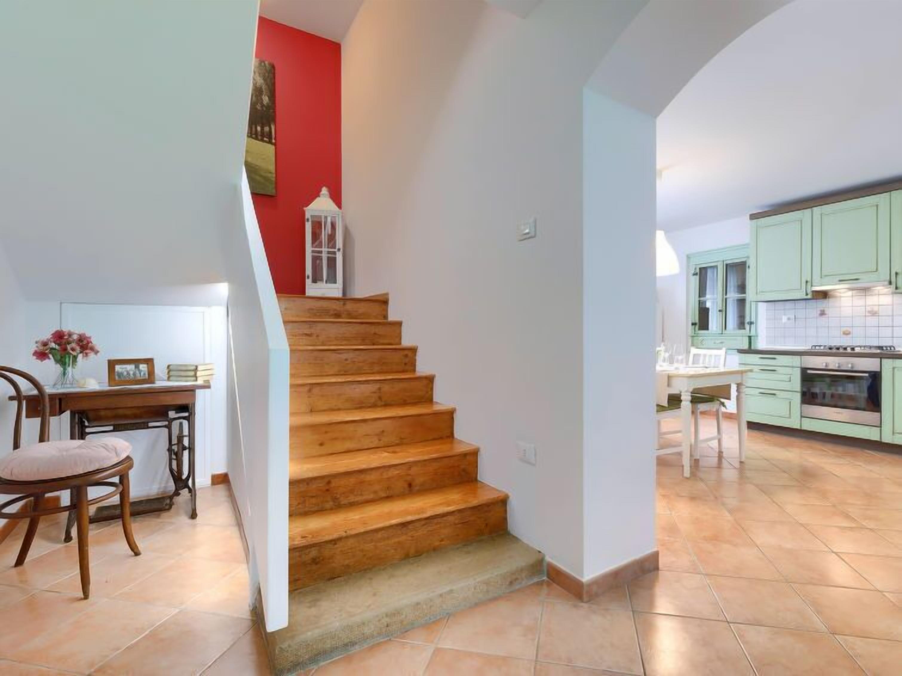 Eine Treppe führt zu einer Küche mit grünen Schränken und Fliesenboden.