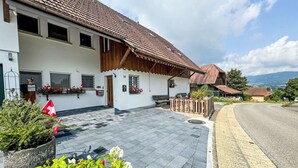 Un chalet traditionnel avec un toit en tuiles, une entrée pavée de pierres et une vue sur le paysage environnant.