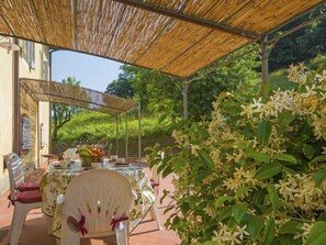 Eine Terrasse im Freien mit Esstisch, Stühlen und einer Bambus-Überdachung.