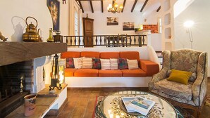 Una sala de estar acogedora con chimenea, un sofá, una silla y un comedor al fondo.