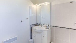 Une salle de bain moderne avec un lavabo blanc, un miroir et une douche.