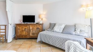 Une chambre à coucher avec un lit, une commode en bois, un téléviseur et une lampe.