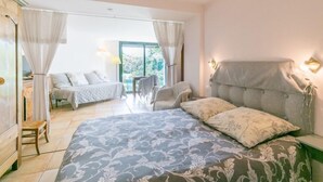 Une chambre avec un grand lit, une chaise, une petite table et une fenêtre avec des rideaux.
