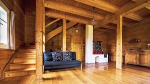 A wooden cabin interior with a wooden staircase, a sofa, a fireplace, and a kitchen area. - Sluneční vršek by Interhome (Kořenov)