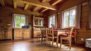 A wooden cabin interior with a dining table, chairs, and a kitchen area with cabinets and a microwave. - Sluneční vršek by Interhome (Kořenov)
