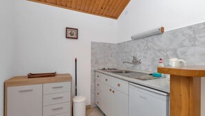 A compact kitchen with white cabinets, a wooden countertop, a sink, and a small trash bin. - Martina by Interhome (Hvar/Pokrivenik)