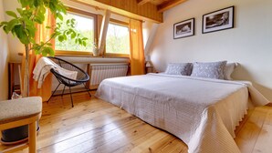 A cozy bedroom with a large bed, a chair, a radiator, and a window with curtains. - Partecznik by Interhome (Wisla)