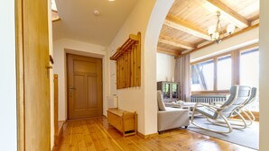 A wooden-floored hallway leading to a living area with a rocking chair and a table, a wooden door, and a radiator. - Partecznik by Interhome (Wisla)