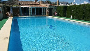 Une piscine rectangulaire à l’eau d’un bleu limpide, entourée d’un mur de pierre et d’une pelouse verdoyante.