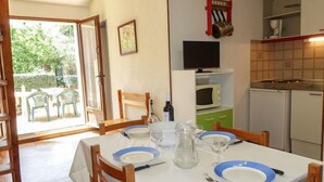 Un comedor con una mesa lista para cuatro, un televisor sobre la barra y vistas al exterior.