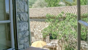 Un bâtiment en pierre avec un toit en tuiles, une table avec un parasol et une vue sur le paysage environnant.