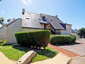 A residential building with a sloped roof, multiple windows, and a well-maintained lawn with hedges.