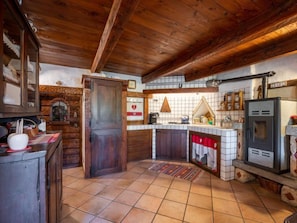 A rustic kitchen with wooden beams, a tiled floor, and a modern stove.