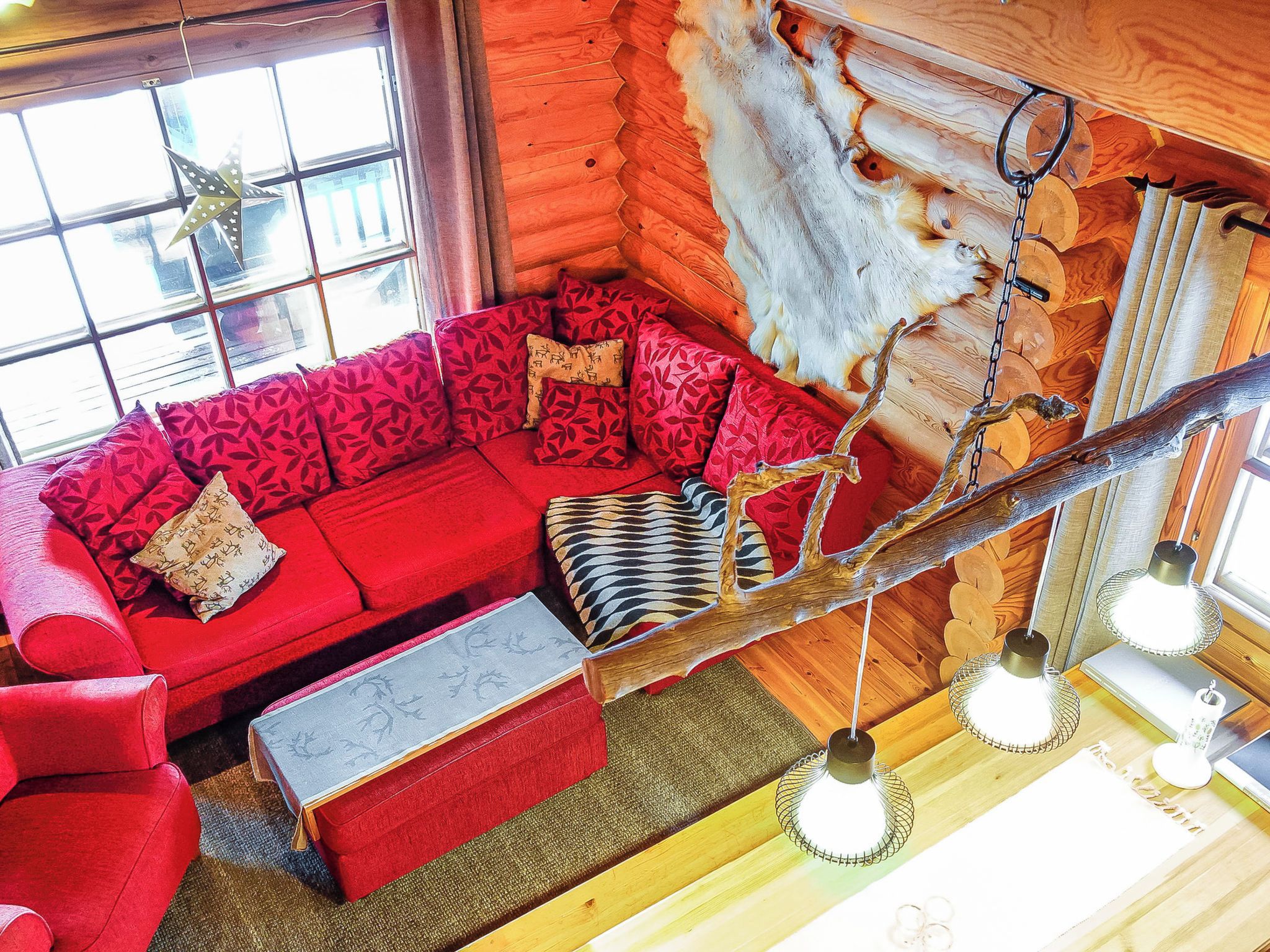 A cozy cabin interior with a red sofa, a wooden bench, and a fur rug.