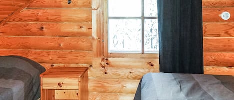 A cabin with a loft-style bedroom, a window with curtains, and a small wooden bench.