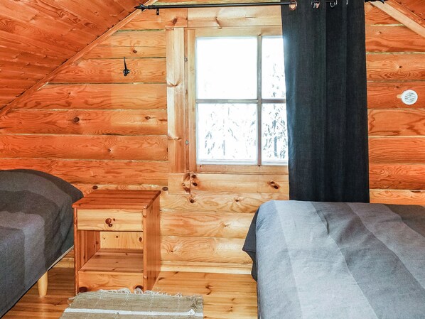 A cabin with a loft-style bedroom, a window with curtains, and a small wooden bench.