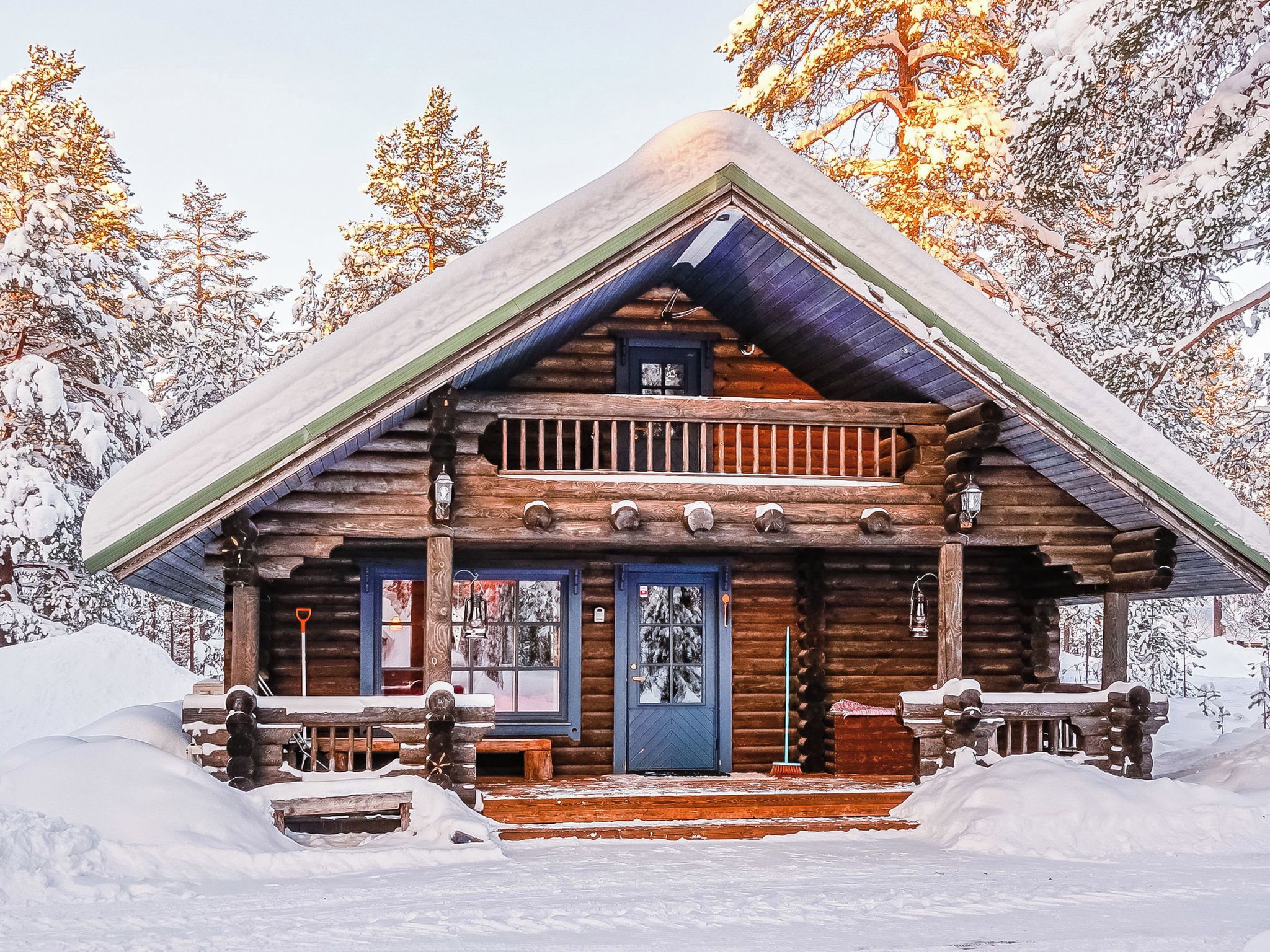A log cabin with a balcony, a front door, and a porch.