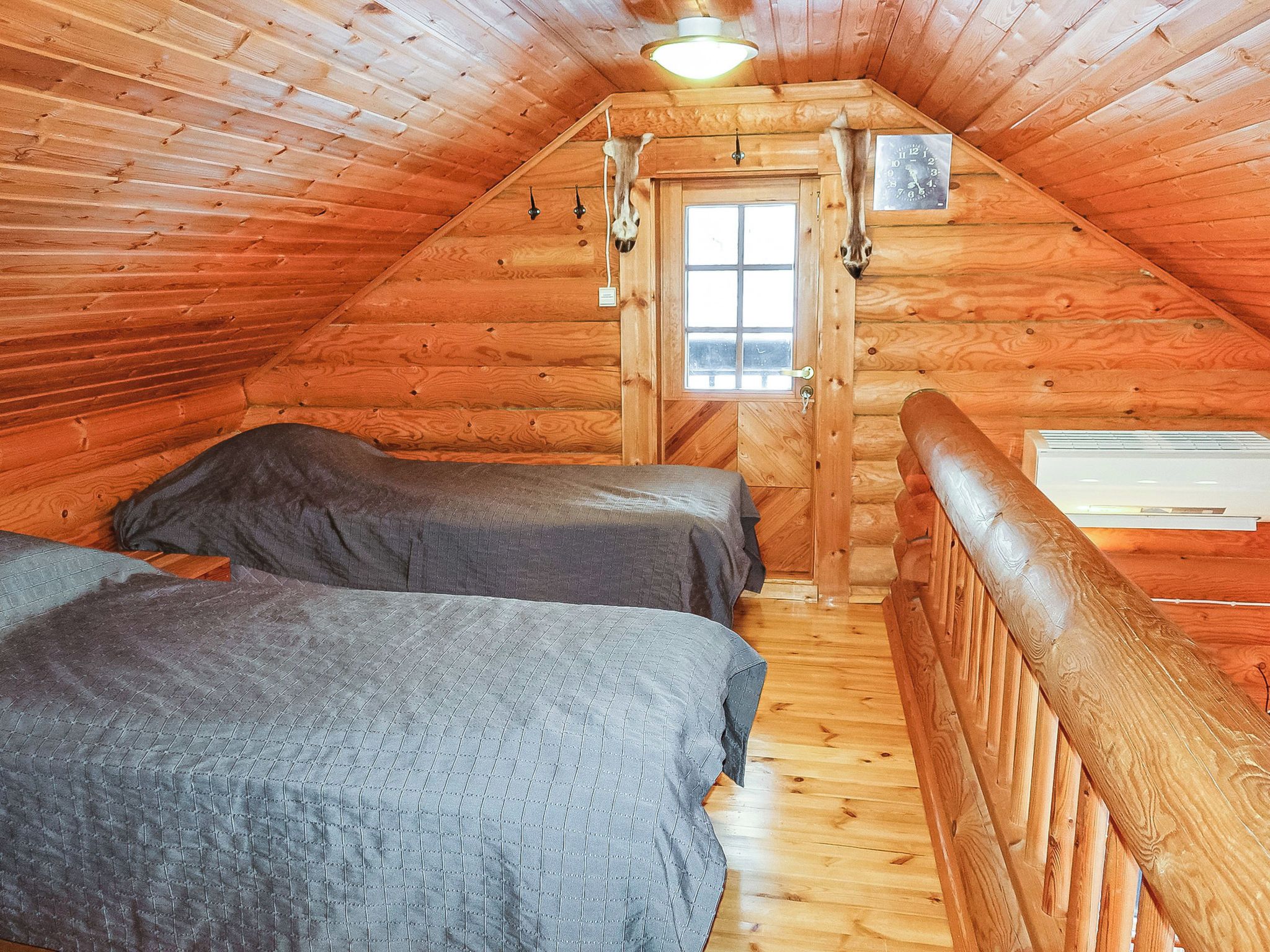 A wooden cabin with two beds, a window, and a door.