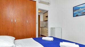Een hotelkamer met een bed, een kledingkast, een schilderij en een kitchenette.