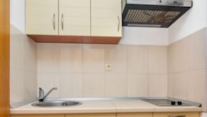 Een keuken met beige kastjes, een roestvrijstalen spoelbak en een zwarte afzuigkap.
