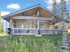 A log cabin with a porch, surrounded by tall grass and trees. - Villa vuosselinjärvi by Interhome (Kuusamo)