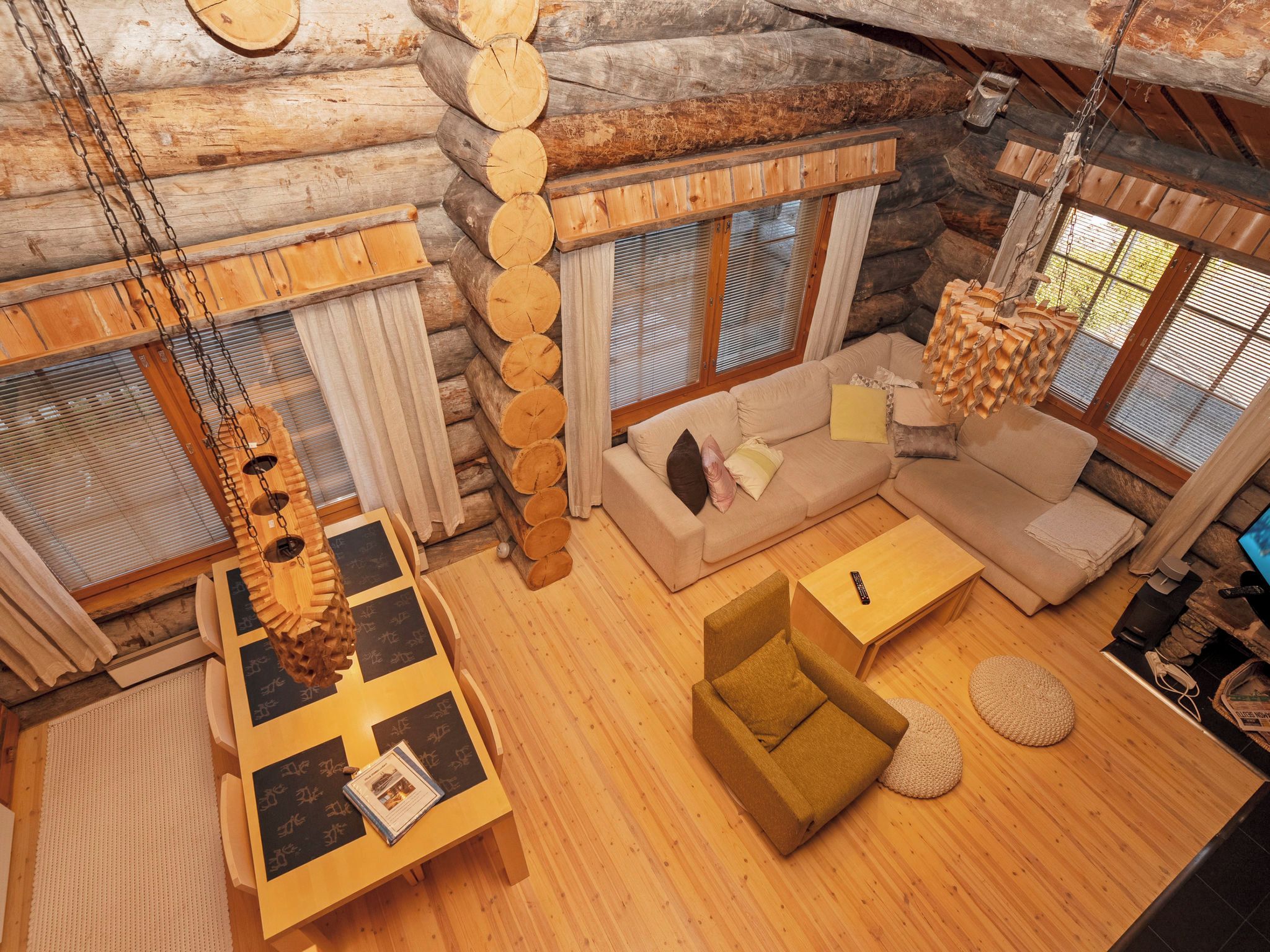 Interior d'una cabana de fusta amb un sofà, una taula i un llum penjant.
