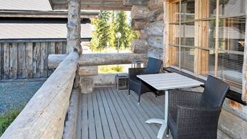 Une terrasse extérieure en bois, avec une table et des chaises, une clôture en bois et une fenêtre avec des stores.