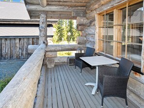 An outdoor wooden deck with a table and chairs, a wooden fence, and a window with blinds. - Villa vuosselinjärvi by Interhome (Kuusamo)