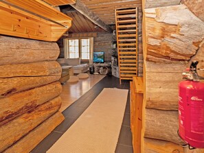 L'intérieur d'une cabane en rondins, avec une cheminée, un coin salon et un téléviseur.