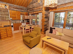 A cozy log cabin interior with a dining area, a sofa, and a kitchen. - Villa vuosselinjärvi by Interhome (Kuusamo)