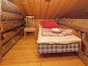 A log cabin bedroom with a bed, a chair, and a red pillow. - Villa vuosselinjärvi by Interhome (Kuusamo)