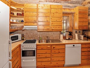 Una cocina funcional con armarios de madera, microondas, estufa, lavaplatos y fregadero.