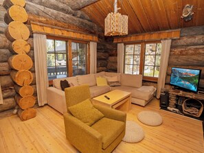 L'intérieur d'une cabane en rondins, avec un canapé, un fauteuil et un téléviseur.