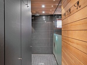 A modern bathroom with a shower, tiled floor, and wooden paneling on one wall. - Villa vuosselinjärvi by Interhome (Kuusamo)