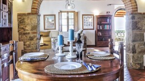 Un comedor con una mesa redonda de madera dispuesta para cuatro personas, debajo de un arco de ladrillo.