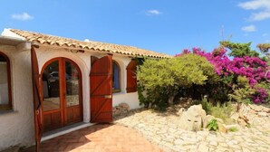 A traditional Mediterranean-style building with a tiled roof, arched doorways, and a stone pathway leading to the entrance. - Apartment Palme by Interhome (Isola Rossa)