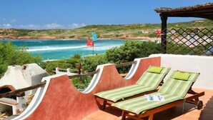 A terrace with two sun loungers, a view of the sea, and a flag. - Apartment Palme by Interhome (Isola Rossa)