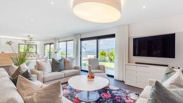 Ein modernes Wohnzimmer mit rundem Couchtisch, Sofas und einem großen Fernseher.
